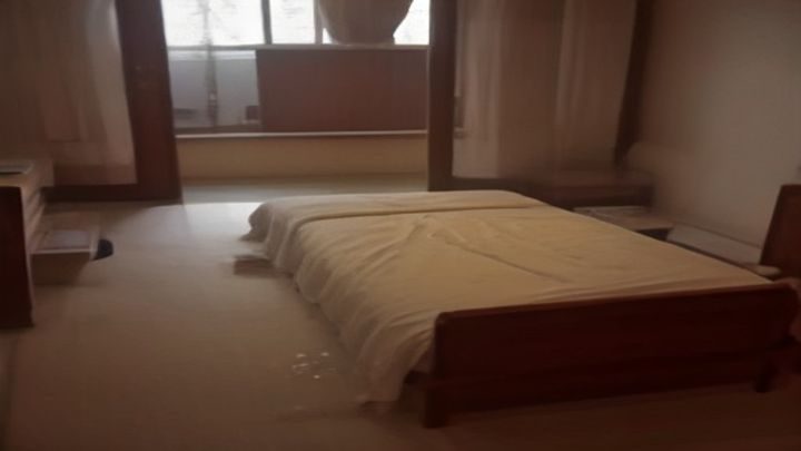 男科医生在诊室内翻阅医学图谱，讲解尿道相关护理方法，背景整洁专业